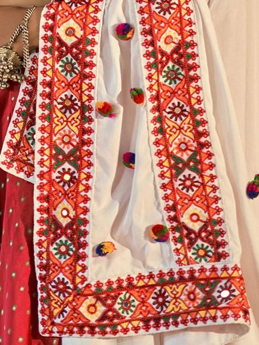 White ethnic kurta with vibrant red, orange, and green embroidery, colorful pom-poms, paired with red salwar