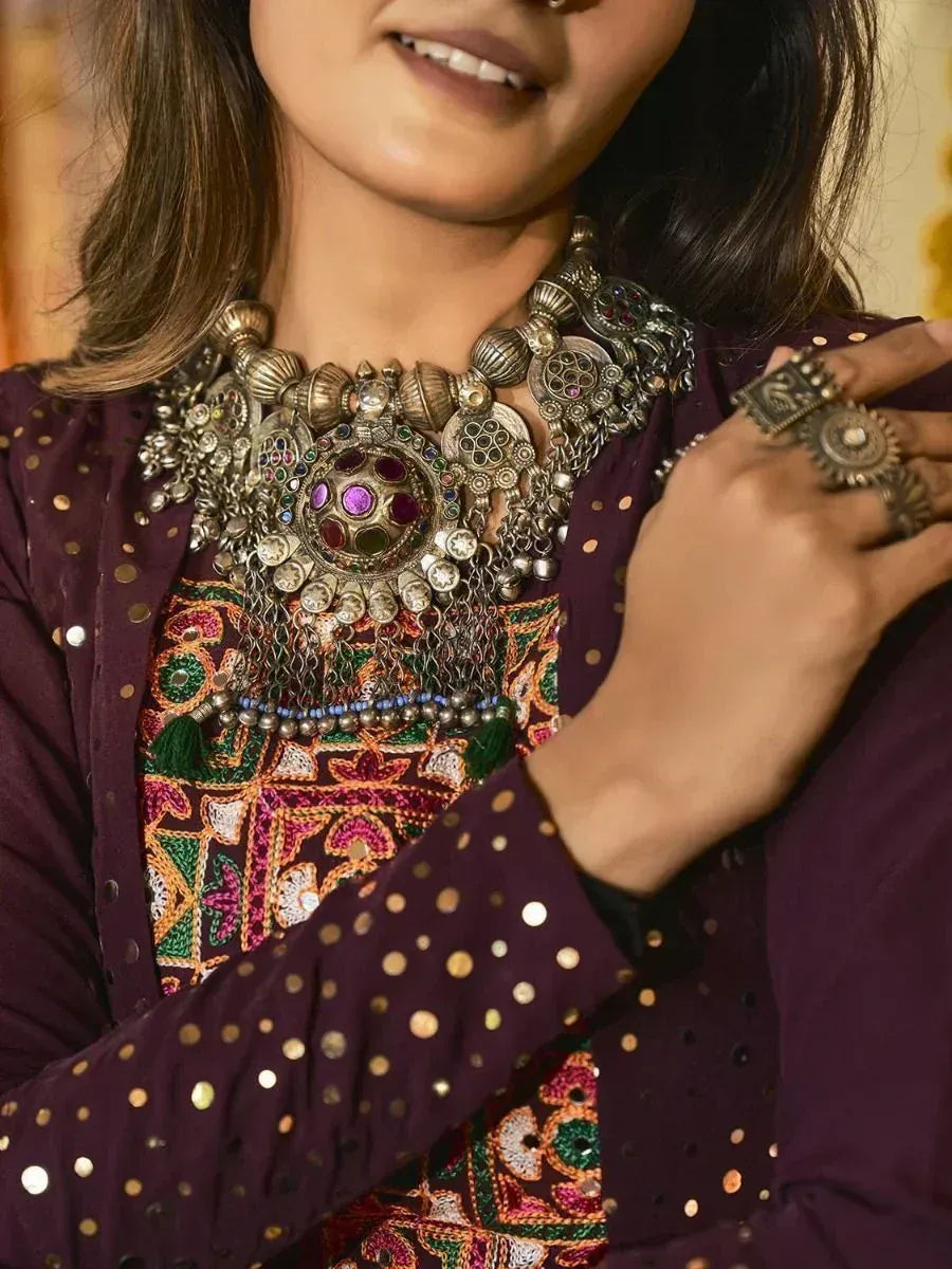 Woman in purple ethnic wear with intricate embroidery and statement jewelry