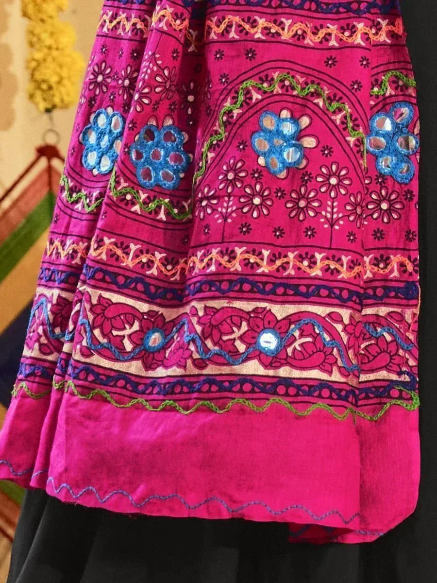 Vibrant pink ethnic skirt with blue mirror work, floral embroidery, and colorful borders for traditional Indian wear