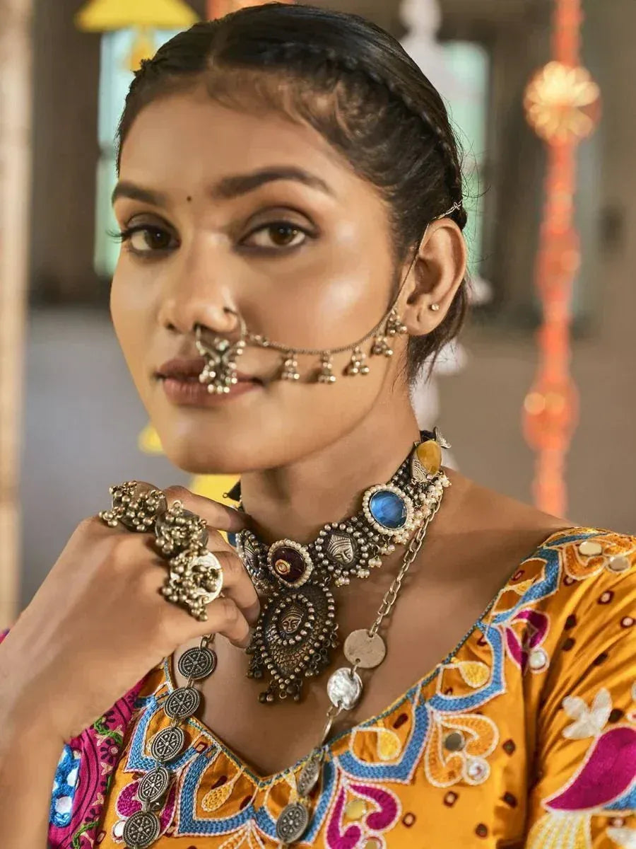 Woman in vibrant ethnic blouse with intricate embroidery and traditional Indian jewelry