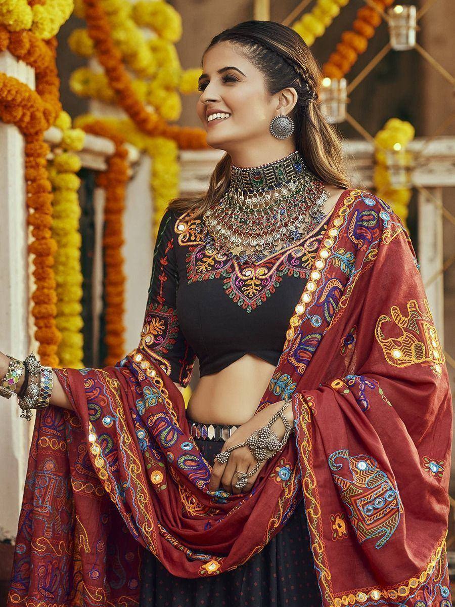 Woman in embroidered black lehenga choli with red dupatta, festive Indian ethnic wear