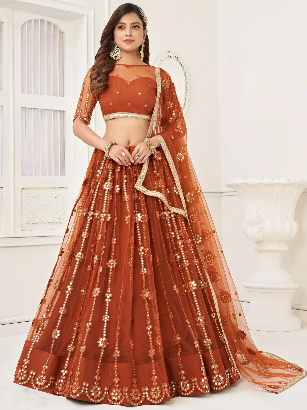 Rust orange designer lehenga choli with gold mirror work, floral embroidery, and sheer dupatta for weddings