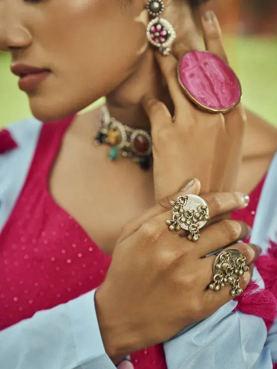 Woman in pink ethnic top with ornate gold rings and statement earrings, showcasing traditional Indian jewelry.