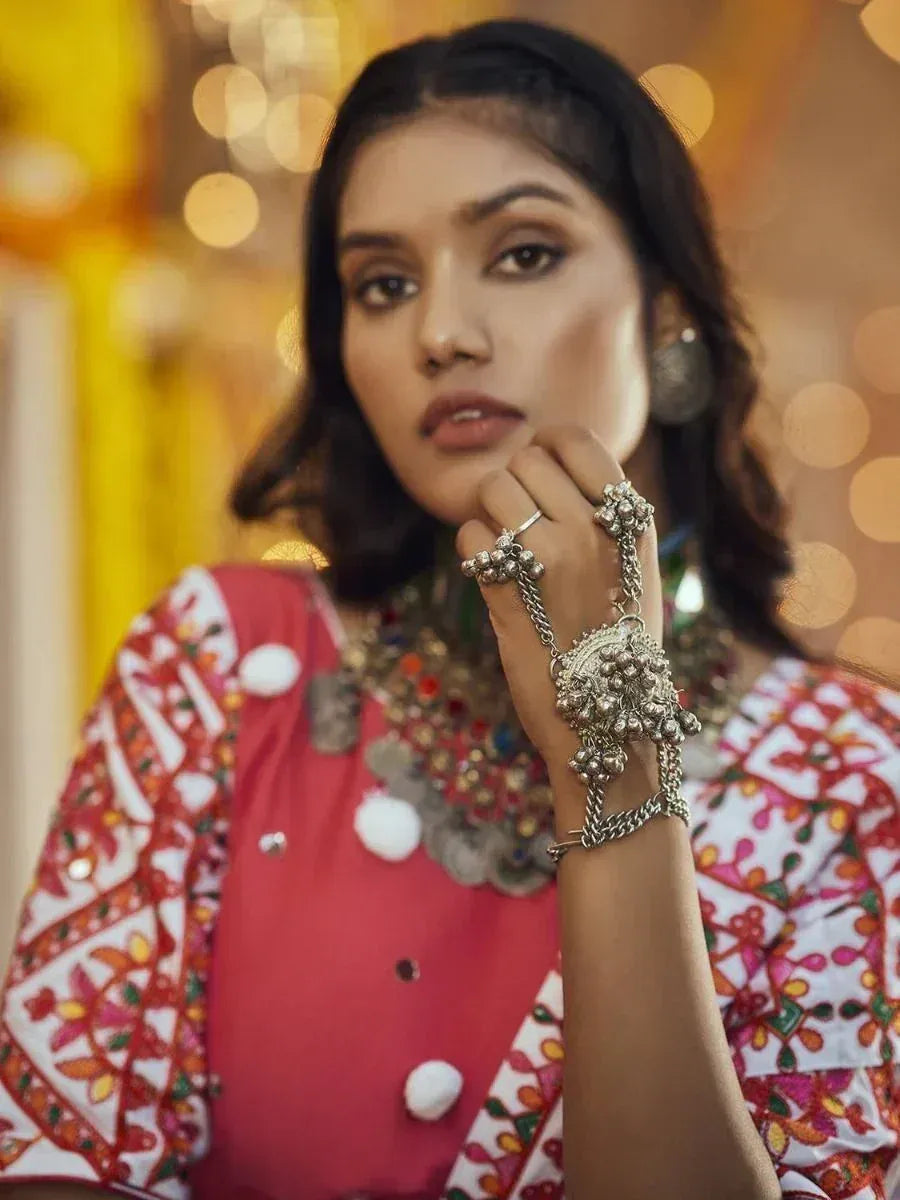 Woman in vibrant embroidered ethnic top with silver jewelry, festive bokeh background