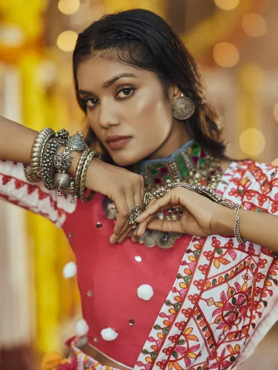 Woman in vibrant red and white embroidered ethnic wear with traditional silver jewelry