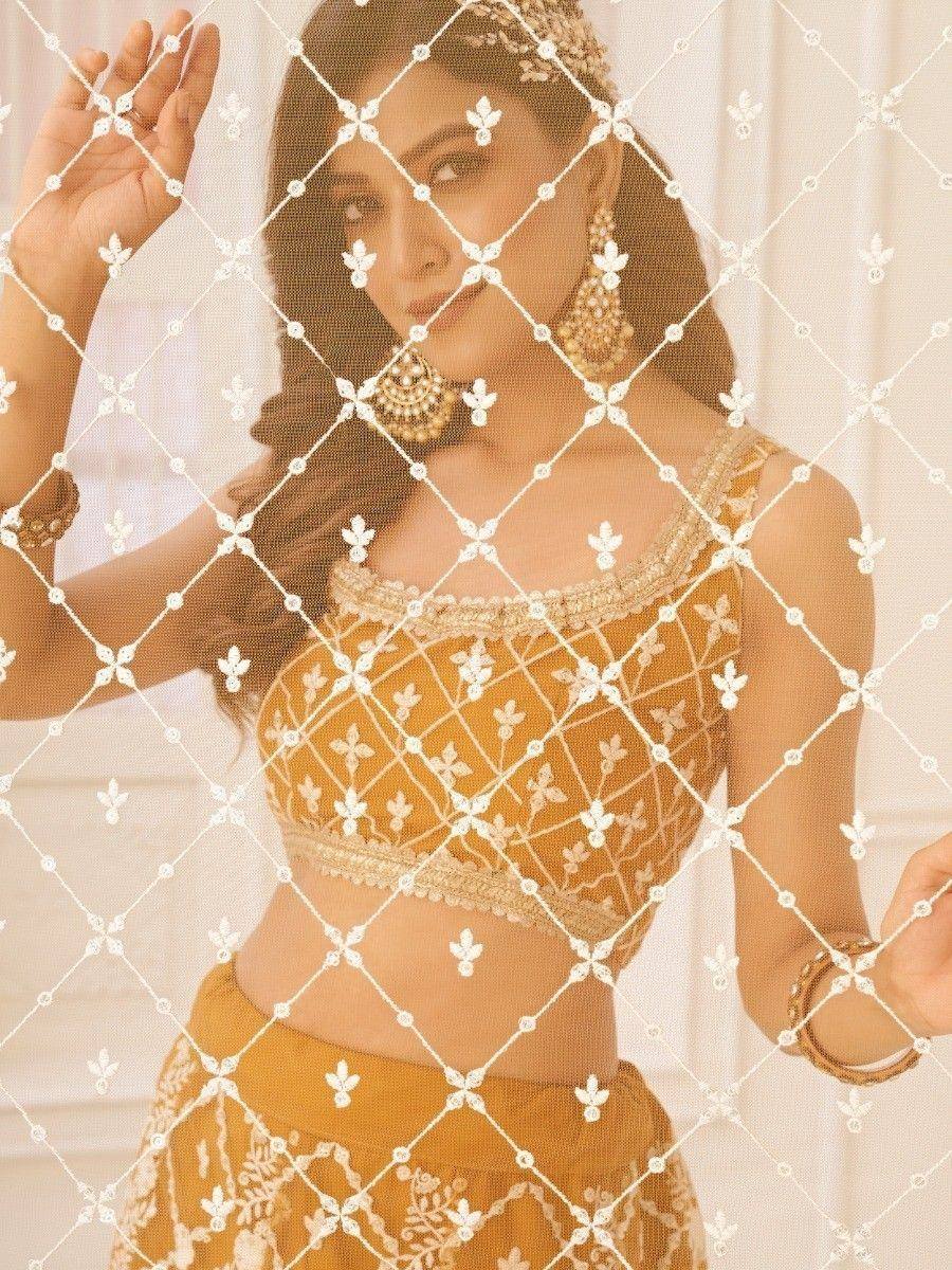 Mustard yellow embroidered lehenga choli with white floral net overlay, traditional Indian ethnic wear