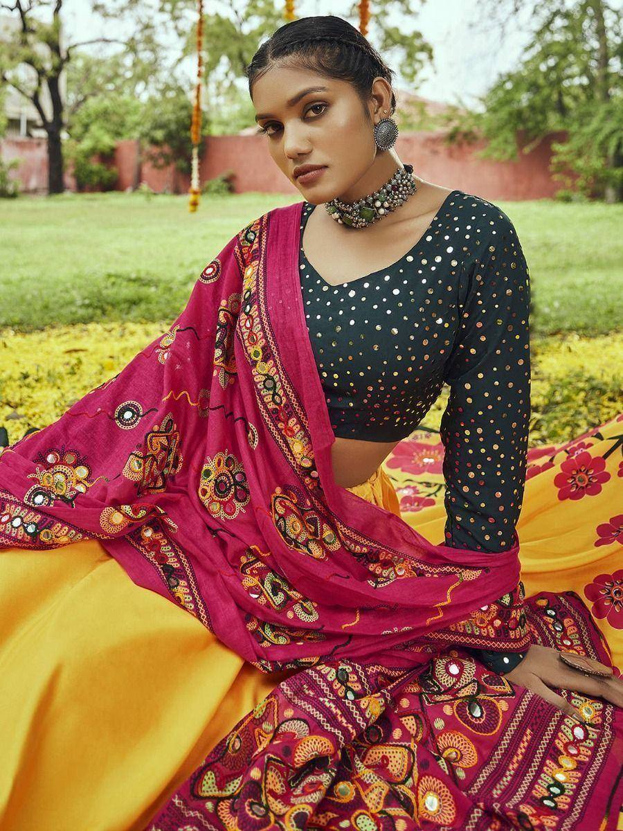 Woman in vibrant ethnic lehenga choli with mirror work, floral dupatta, and traditional jewelry