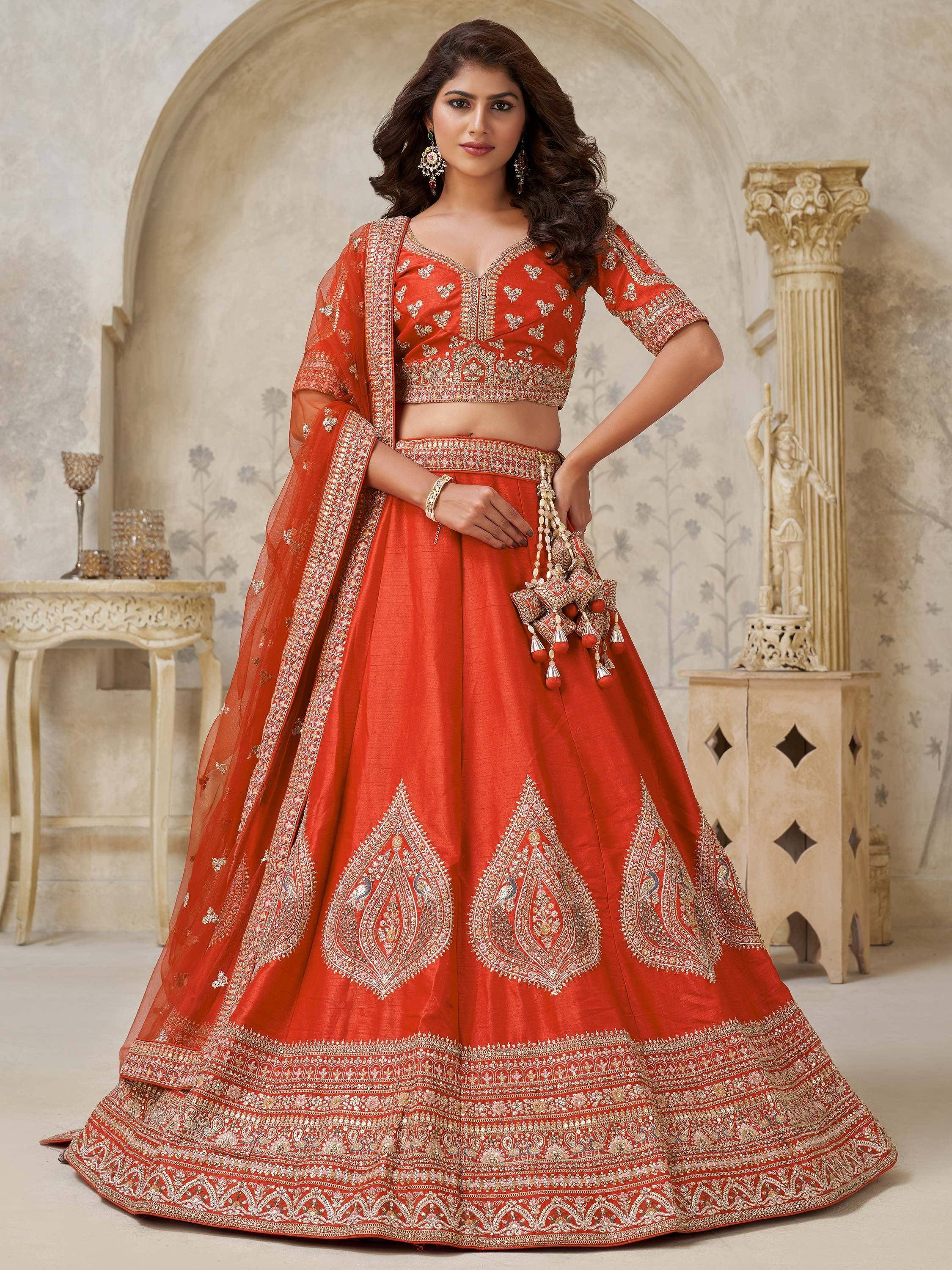 Orange designer lehenga choli with heavy embroidery and peacock motifs, perfect for weddings and festive occasions.