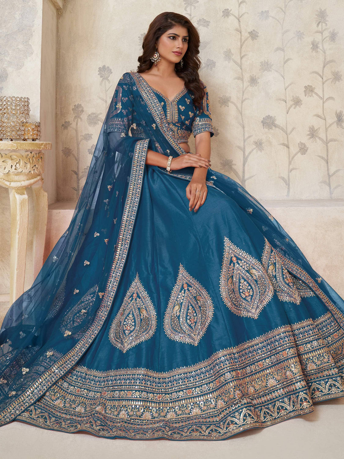 Teal blue designer lehenga choli with intricate gold embroidery and paisley motifs, perfect for Indian ethnic occasions.