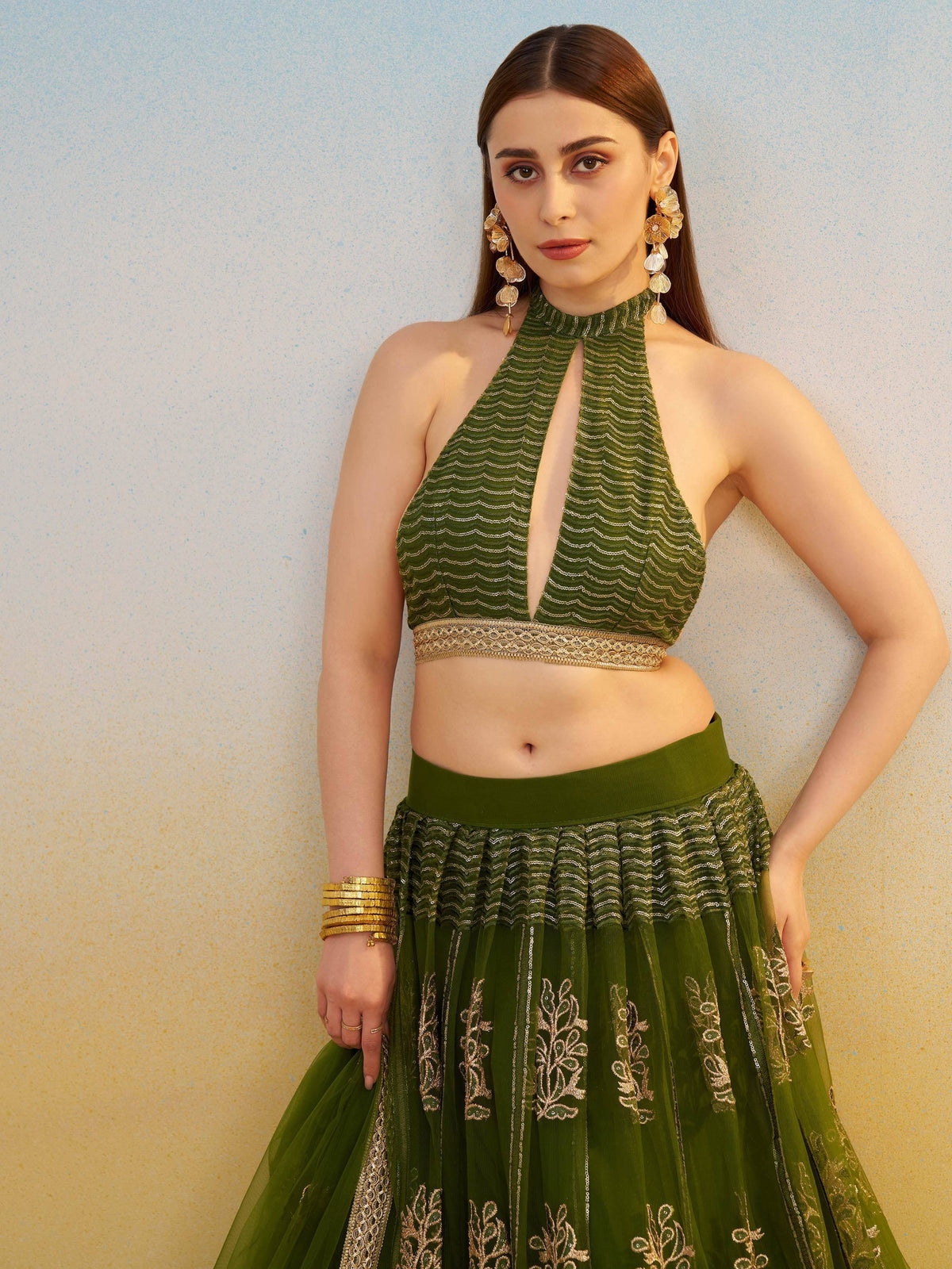 Green embroidered lehenga choli with halter neck top and gold jewelry for Indian ethnic wear