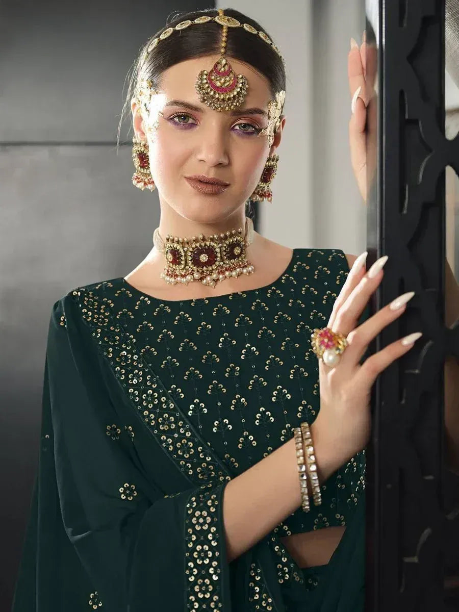 Elegant woman in dark green sequined ethnic gown with traditional Indian jewelry and maang tikka