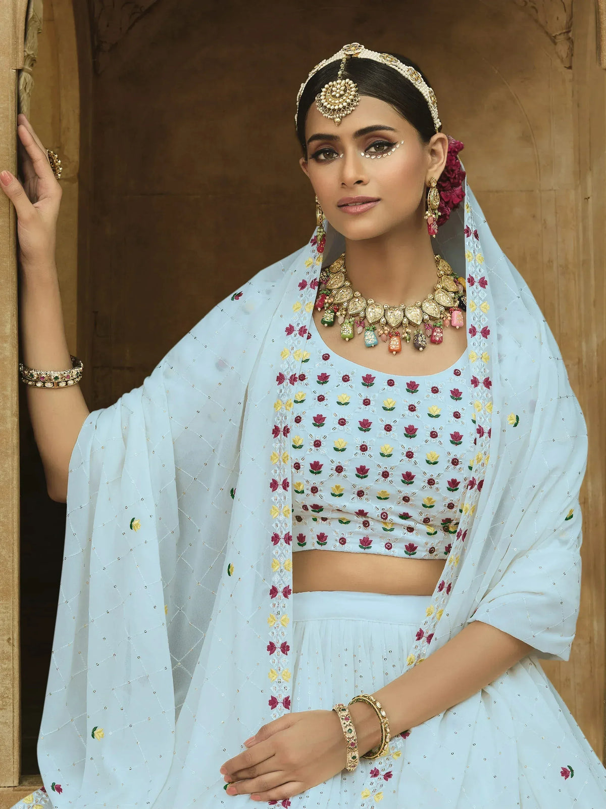 Light blue embroidered lehenga choli with floral motifs, paired with traditional jewelry and dupatta.