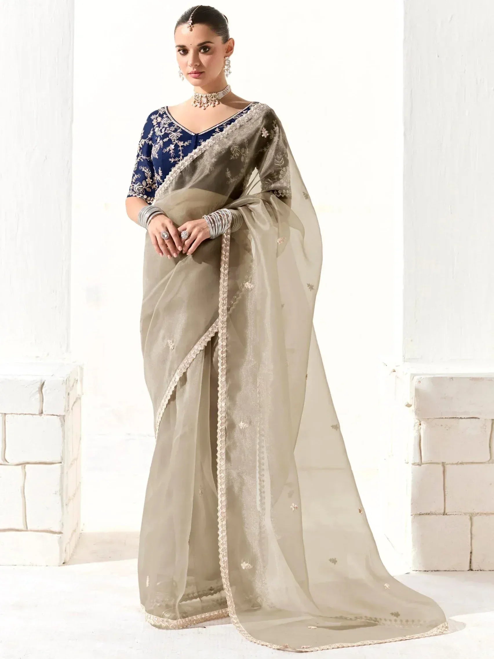 Elegant beige saree with gold embroidery and navy blue blouse, perfect for Indian ethnic occasions.