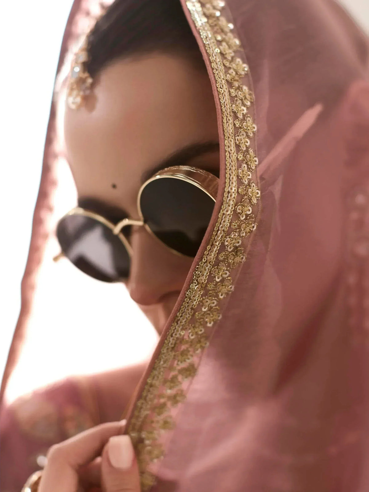 Pink ethnic dupatta with gold sequin border, styled with sunglasses for modern Indian wear