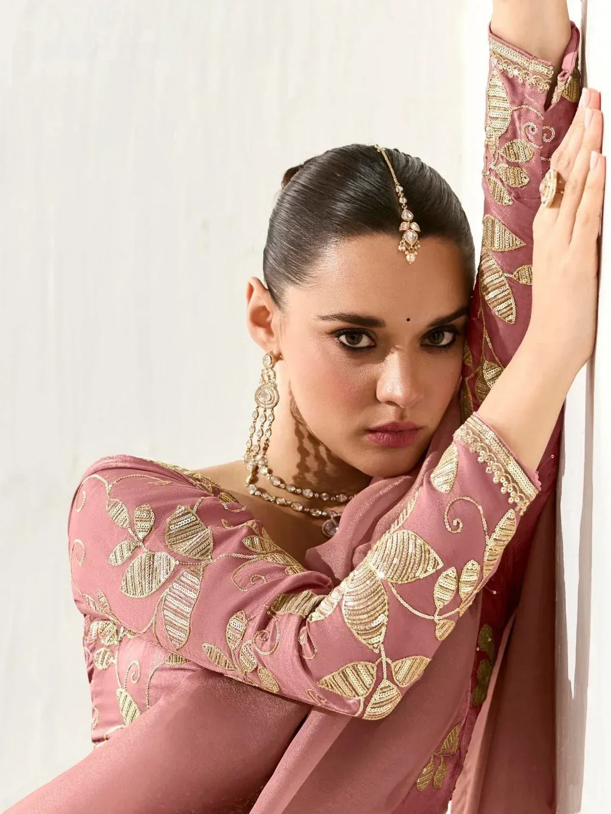 Elegant pink ethnic gown with gold leaf embroidery, paired with traditional jewelry for festive occasions
