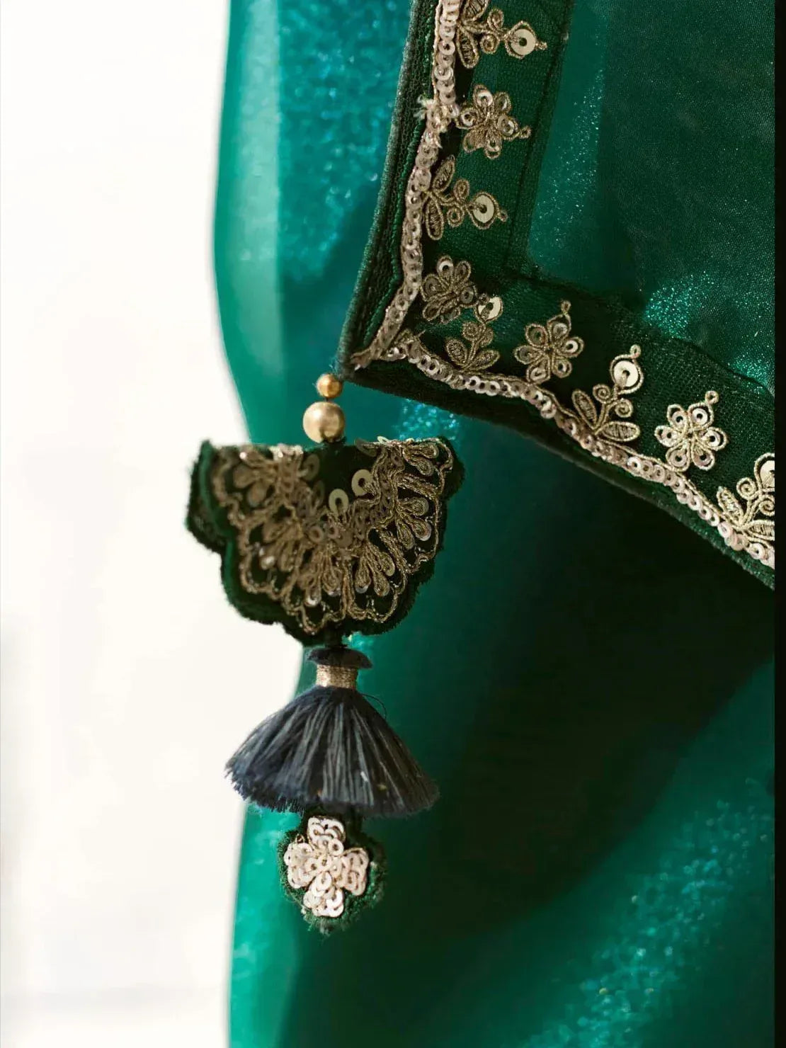 Emerald green ethnic wear with gold embroidery and tassel detail, perfect for Indian designer lehenga or saree