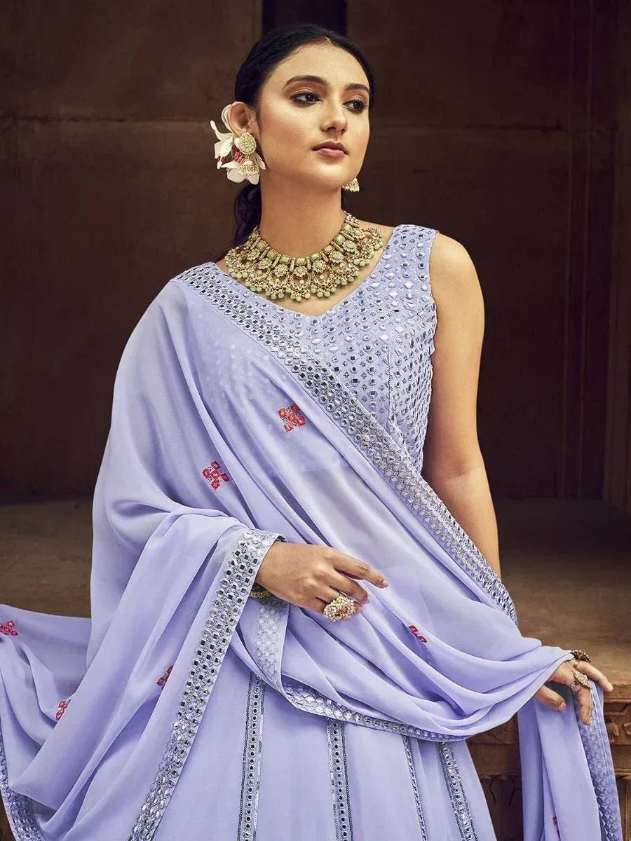 Lavender designer saree with mirror work and red embroidery, paired with statement jewelry for ethnic occasions