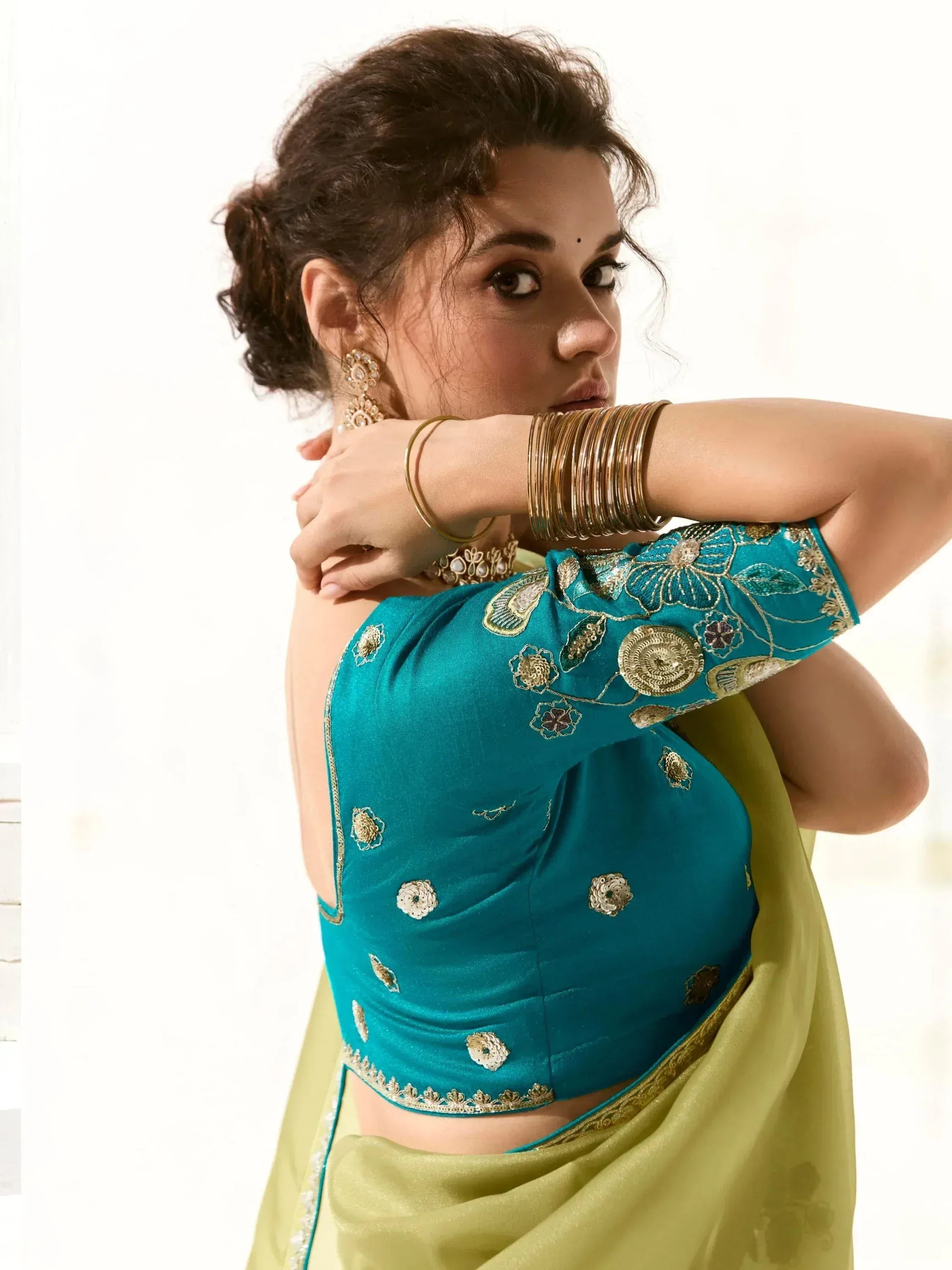 Teal embroidered saree blouse with gold detailing, paired with olive green saree, styled with traditional bangles and earrings