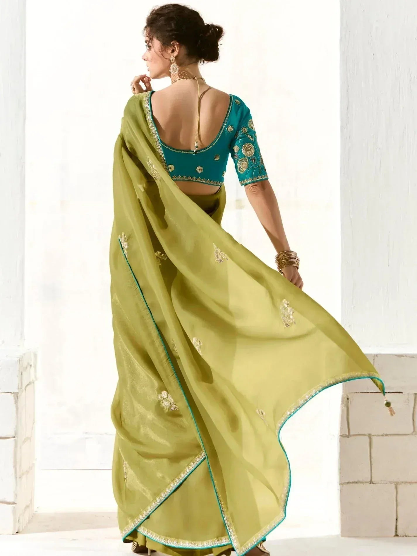 Elegant green saree with teal blouse, gold embroidery, and backless design for Indian ethnic wear
