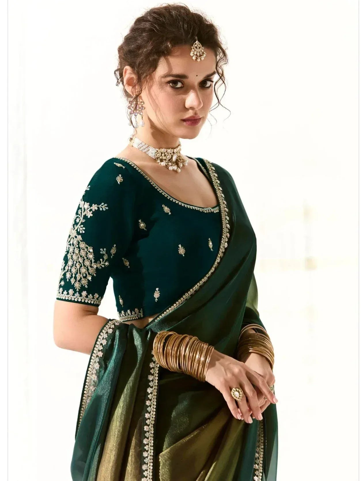 Emerald green designer saree with gold embroidery and matching blouse, styled with traditional jewelry