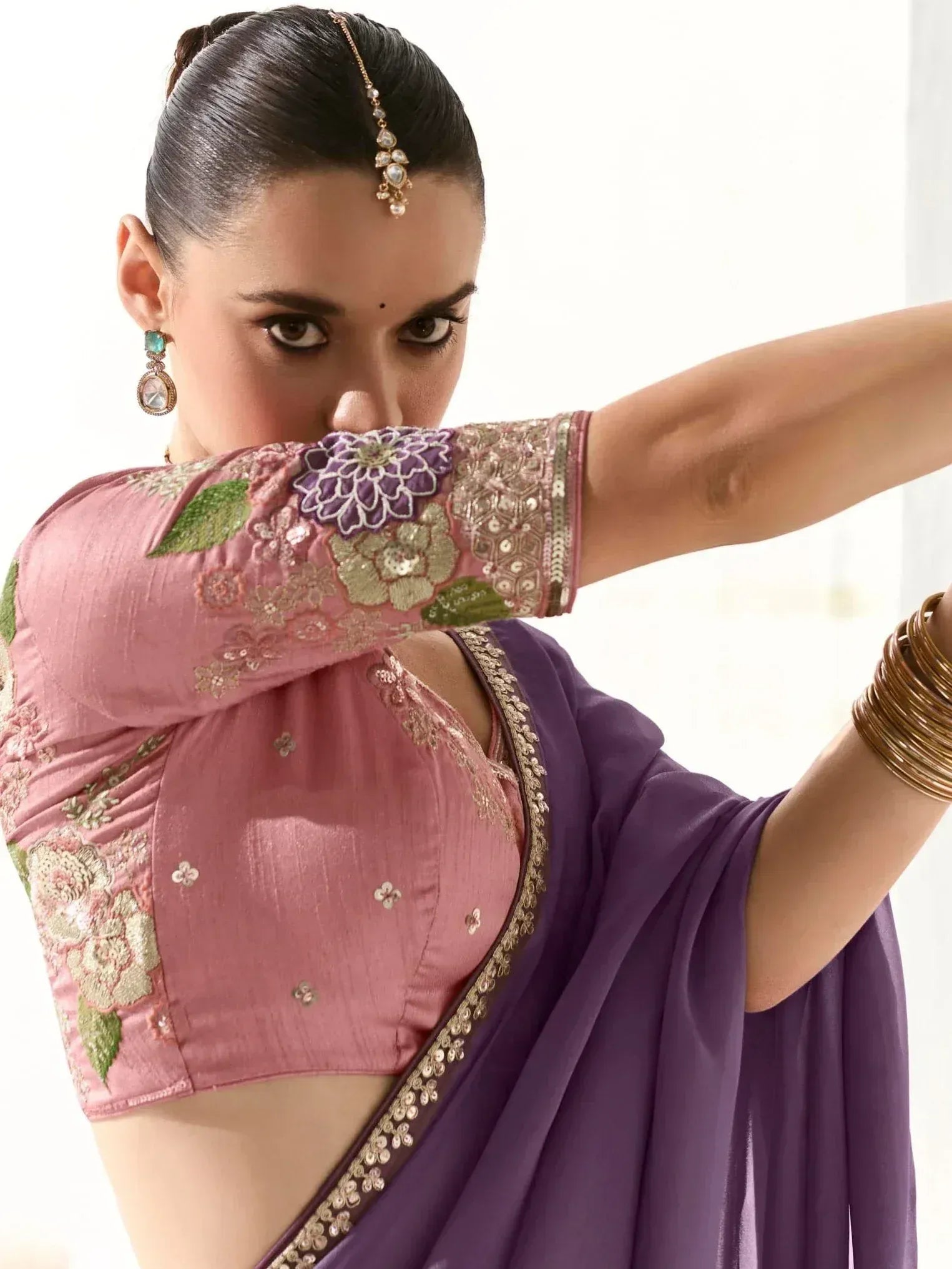 Woman in purple saree with pink floral blouse, traditional Indian ethnic wear, adorned with maang tikka and earrings
