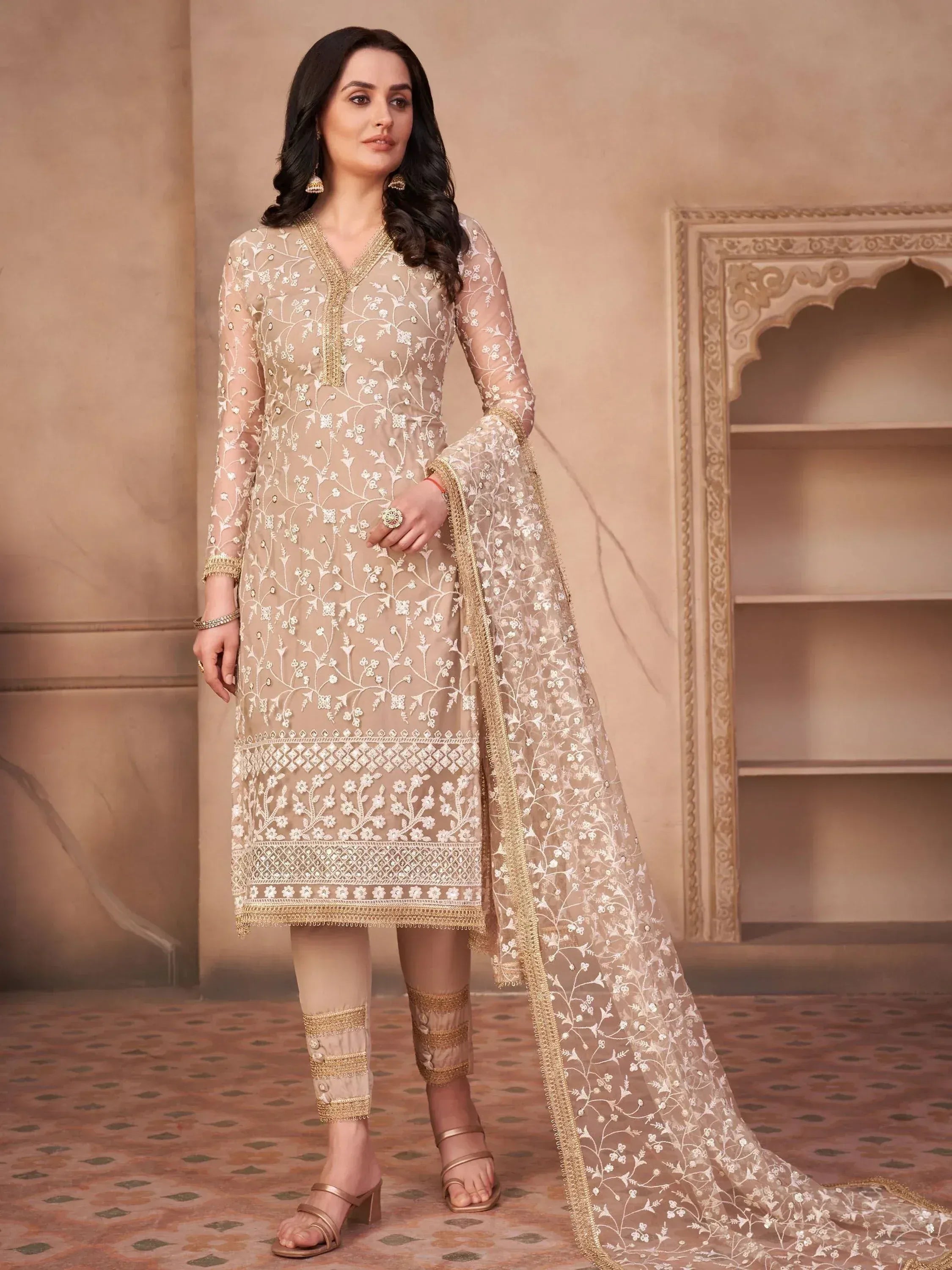 Woman wearing beige embroidered salwar kameez with matching dupatta in ethnic setting