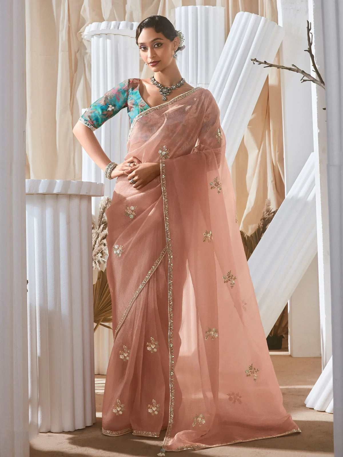 Elegant peach saree with floral embroidery and gold border, paired with a colorful blouse for Indian ethnic wear.