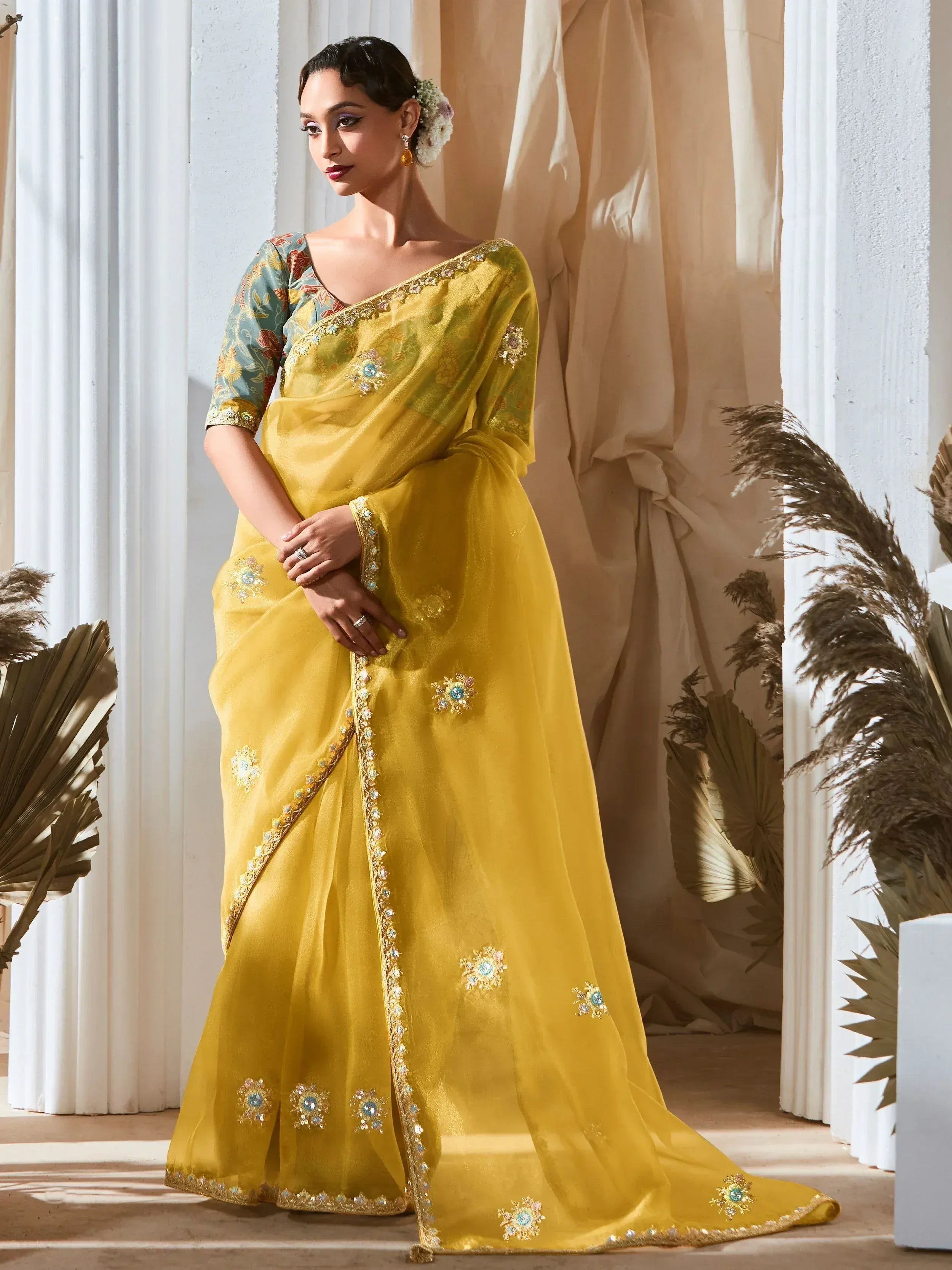 Yellow embroidered saree with floral motifs and embellished border, paired with printed blouse for ethnic wear