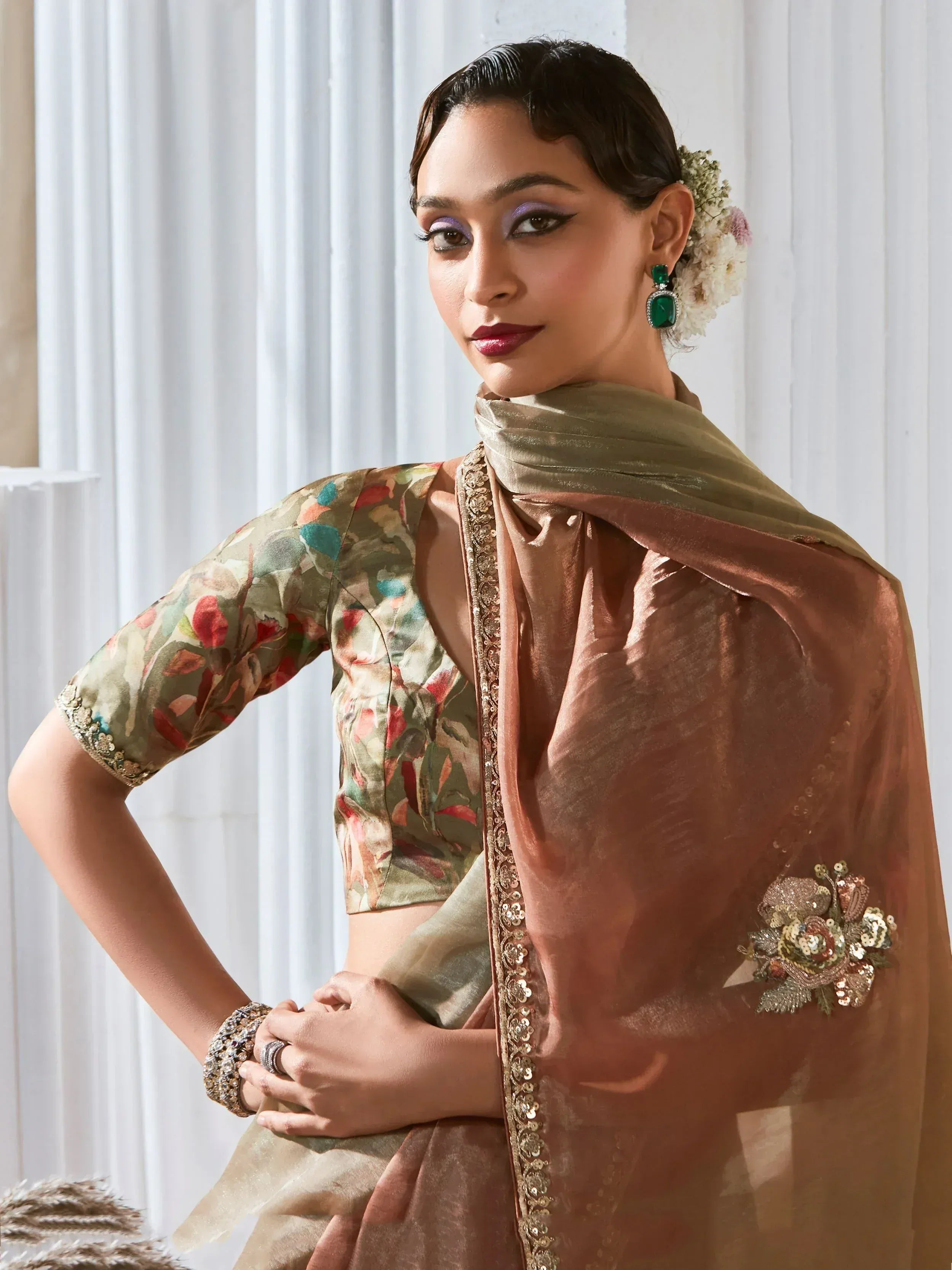 Woman in floral blouse and embroidered saree, Indian ethnic wear with green earrings and floral hair accessory