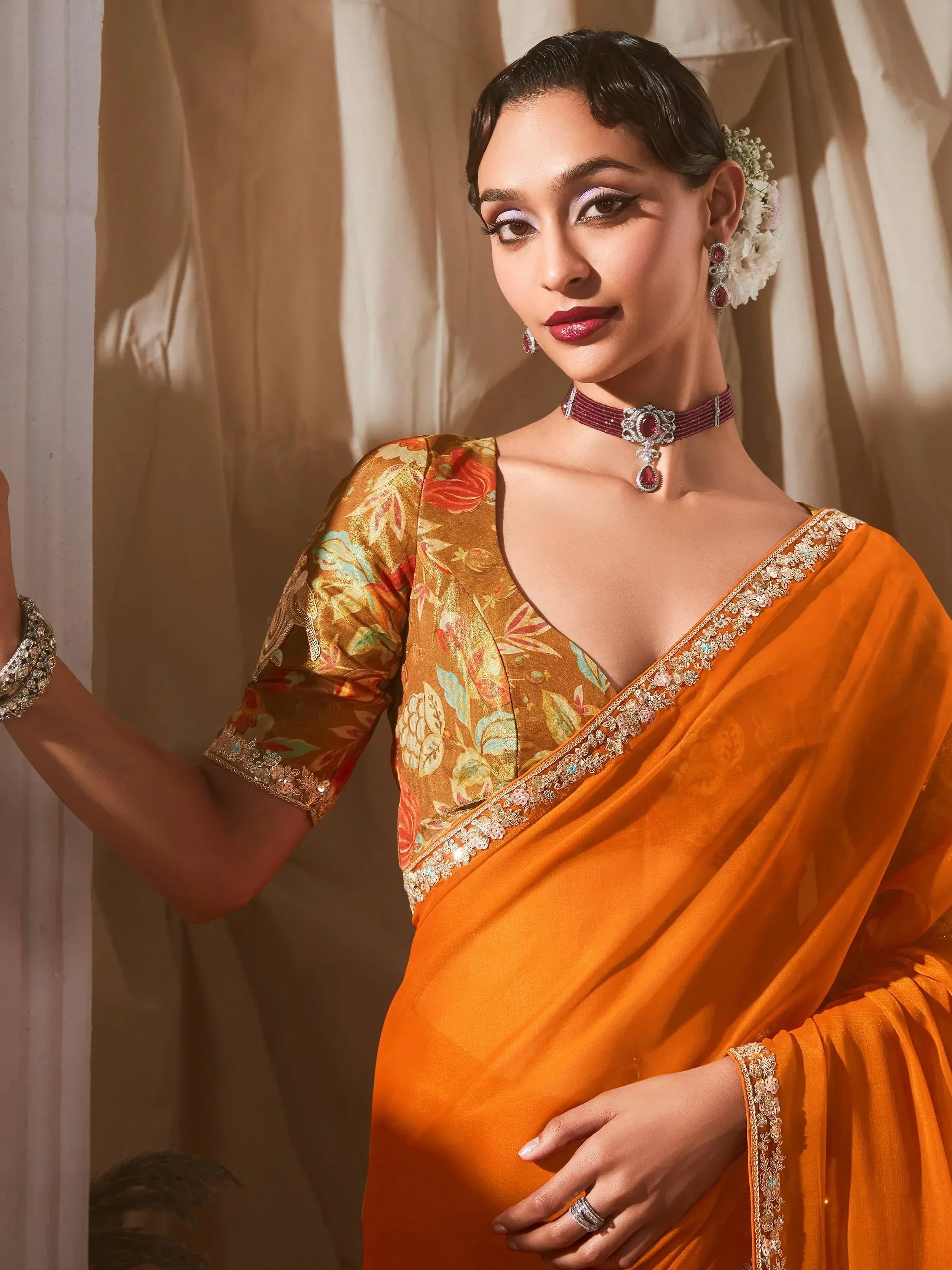 Orange saree with floral blouse, ethnic jewelry, and elegant styling for Indian occasions
