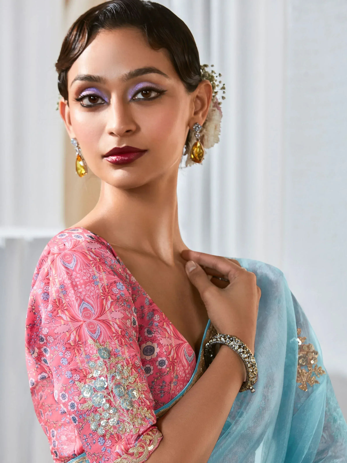 Woman in pink floral blouse and blue saree with gold embroidery, styled for Indian ethnic wear