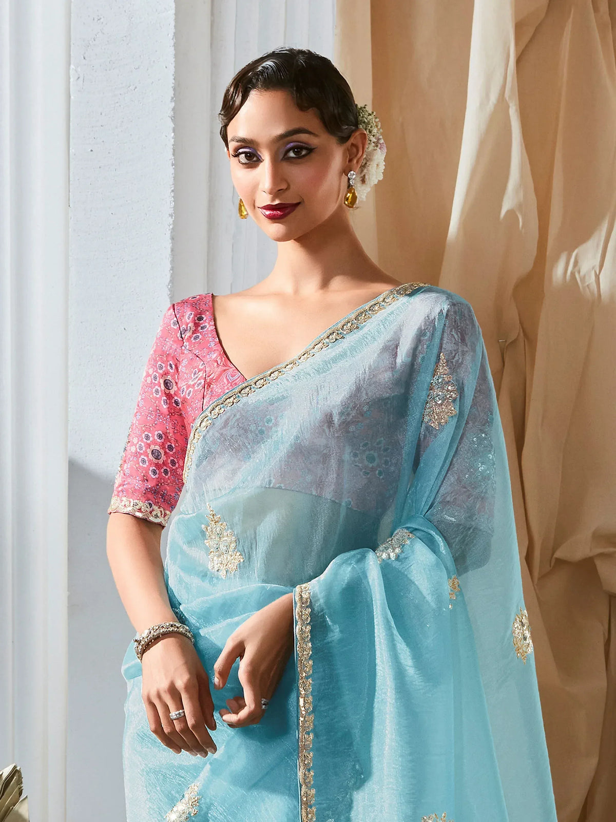 Elegant light blue saree with gold embroidery and pink floral blouse, perfect for Indian ethnic occasions.