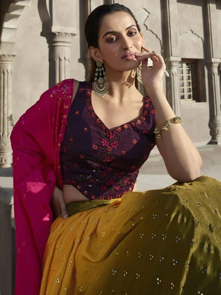 Woman in purple floral blouse, mustard lehenga, and pink dupatta with traditional jewelry