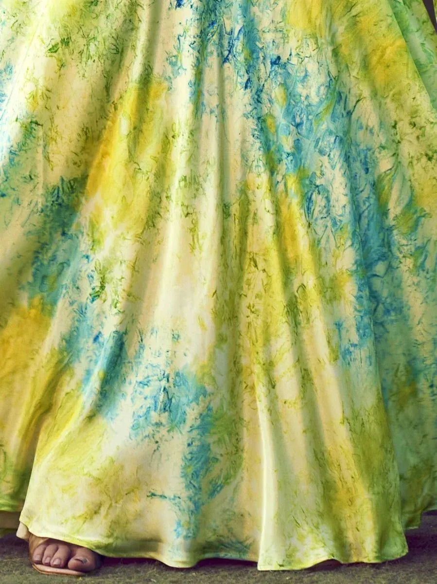 Vibrant yellow and blue tie-dye ethnic gown with flowing fabric, perfect for festive occasions.
