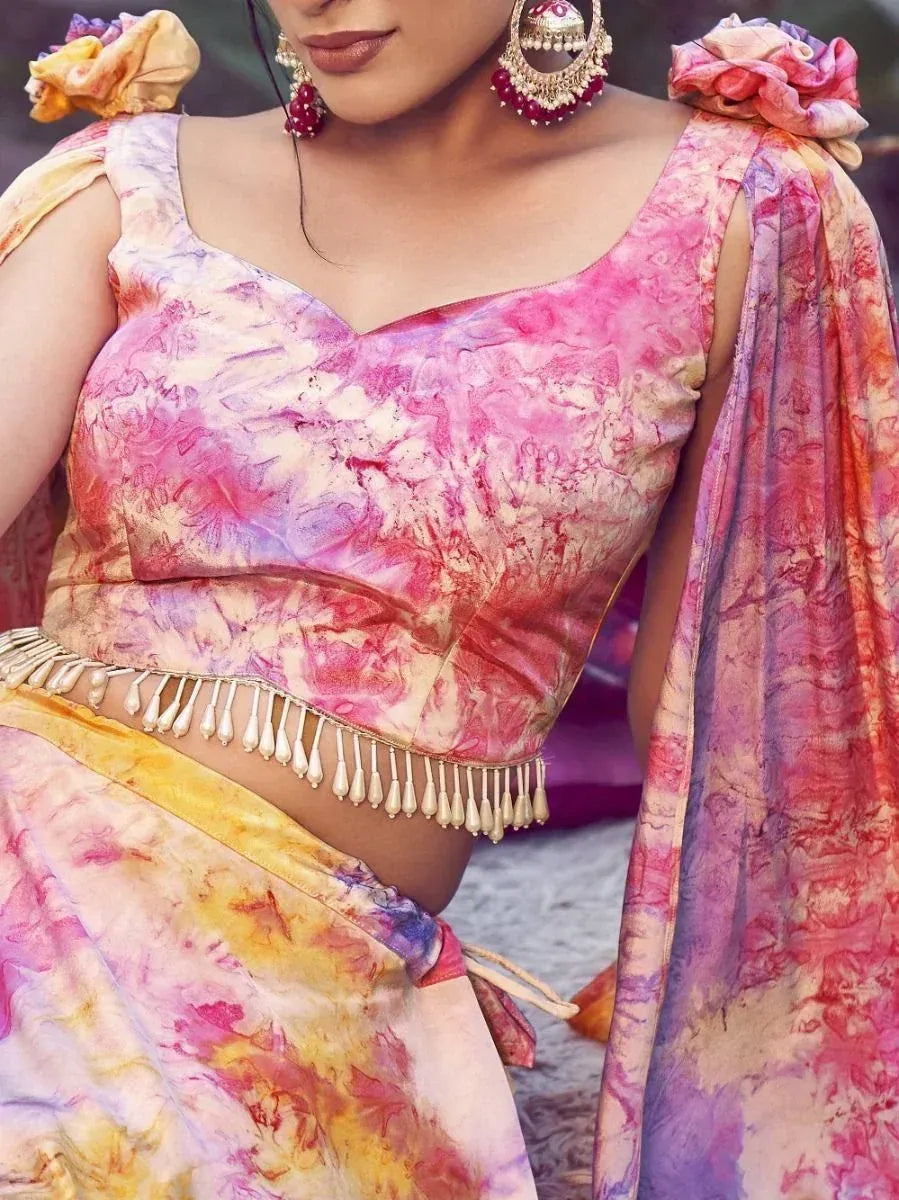 Vibrant tie-dye lehenga choli with floral shoulder details and gold tassels, perfect for Indian ethnic wear