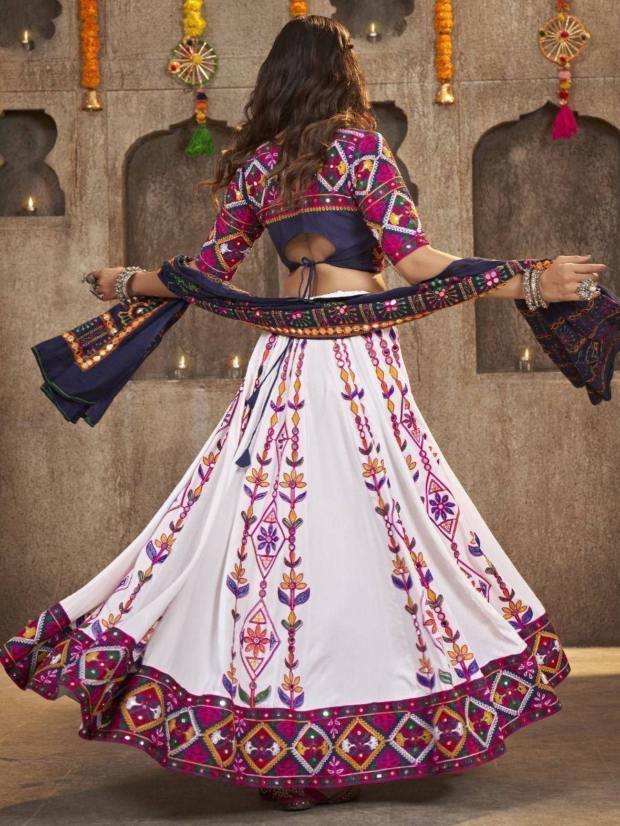 Woman in colorful embroidered lehenga choli with mirror work, twirling against festive Indian backdrop