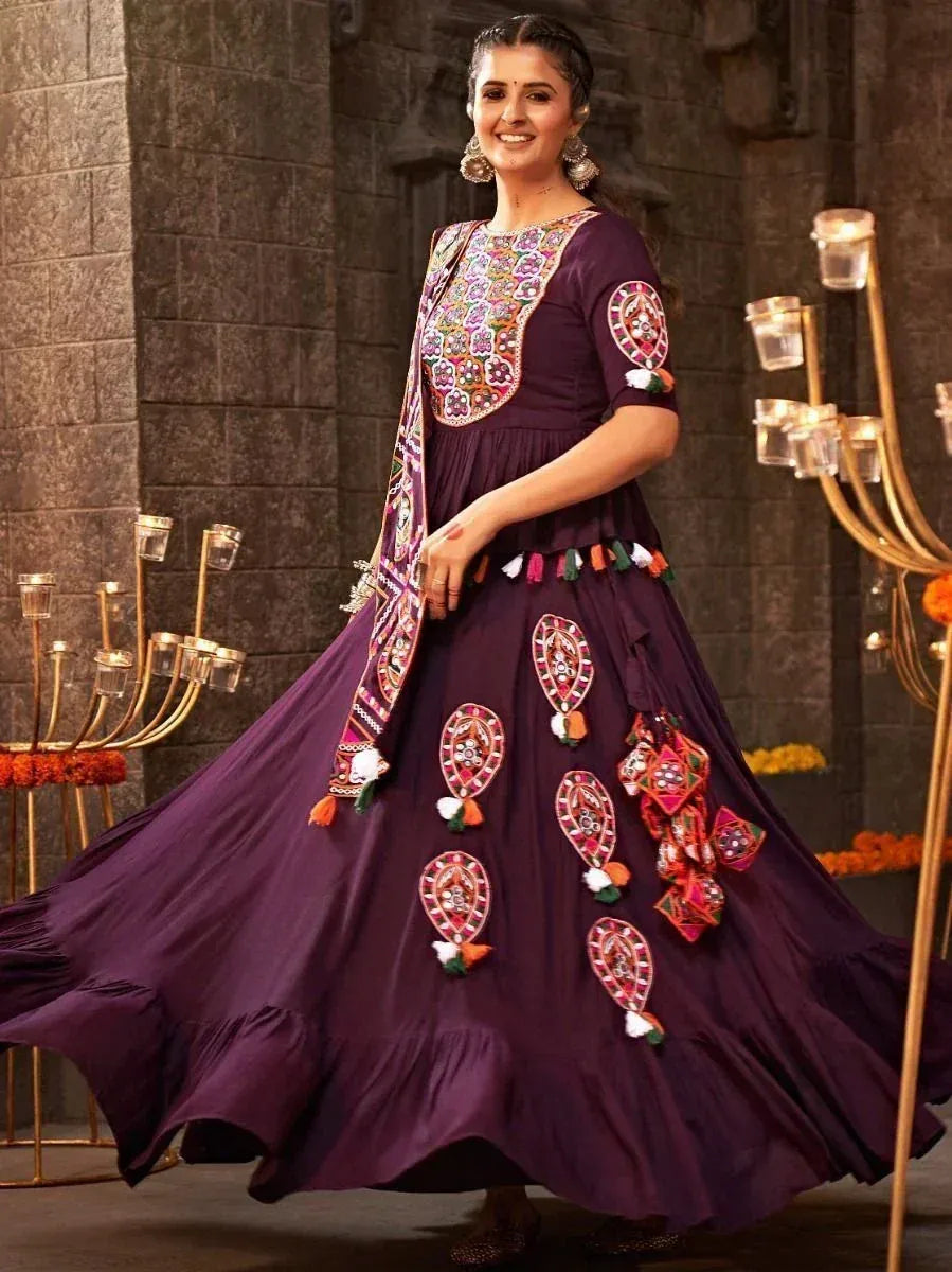 Purple ethnic gown with colorful mirror work and tassels, perfect for festive occasions