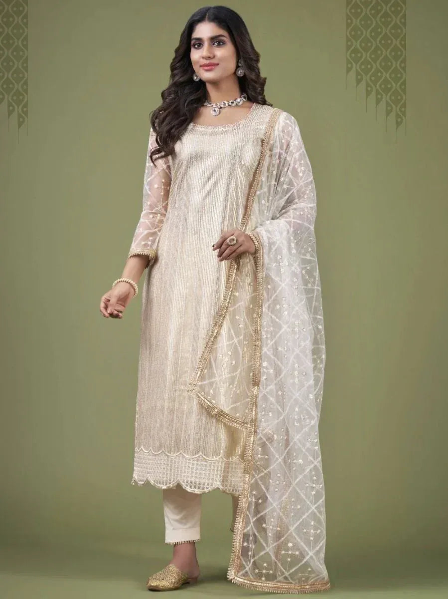 Woman wearing a cream embroidered salwar kameez with sheer dupatta and gold juttis
