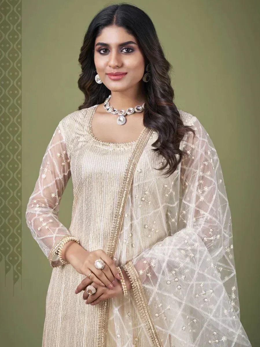 Woman wearing cream embroidered ethnic gown with sheer dupatta and statement jewelry