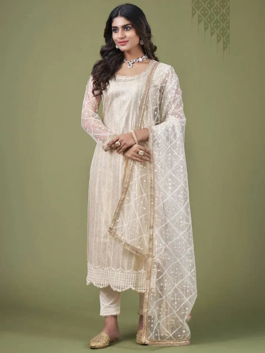 Woman wearing cream embroidered salwar kameez with sheer dupatta and ethnic jewelry