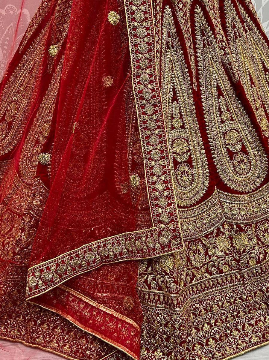 Red velvet lehenga with intricate gold embroidery and floral motifs, perfect for Indian weddings and festive occasions.