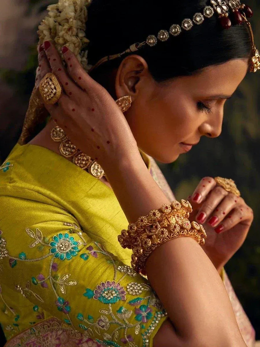 Woman in yellow embroidered saree with gold jewelry and floral hair accessory
