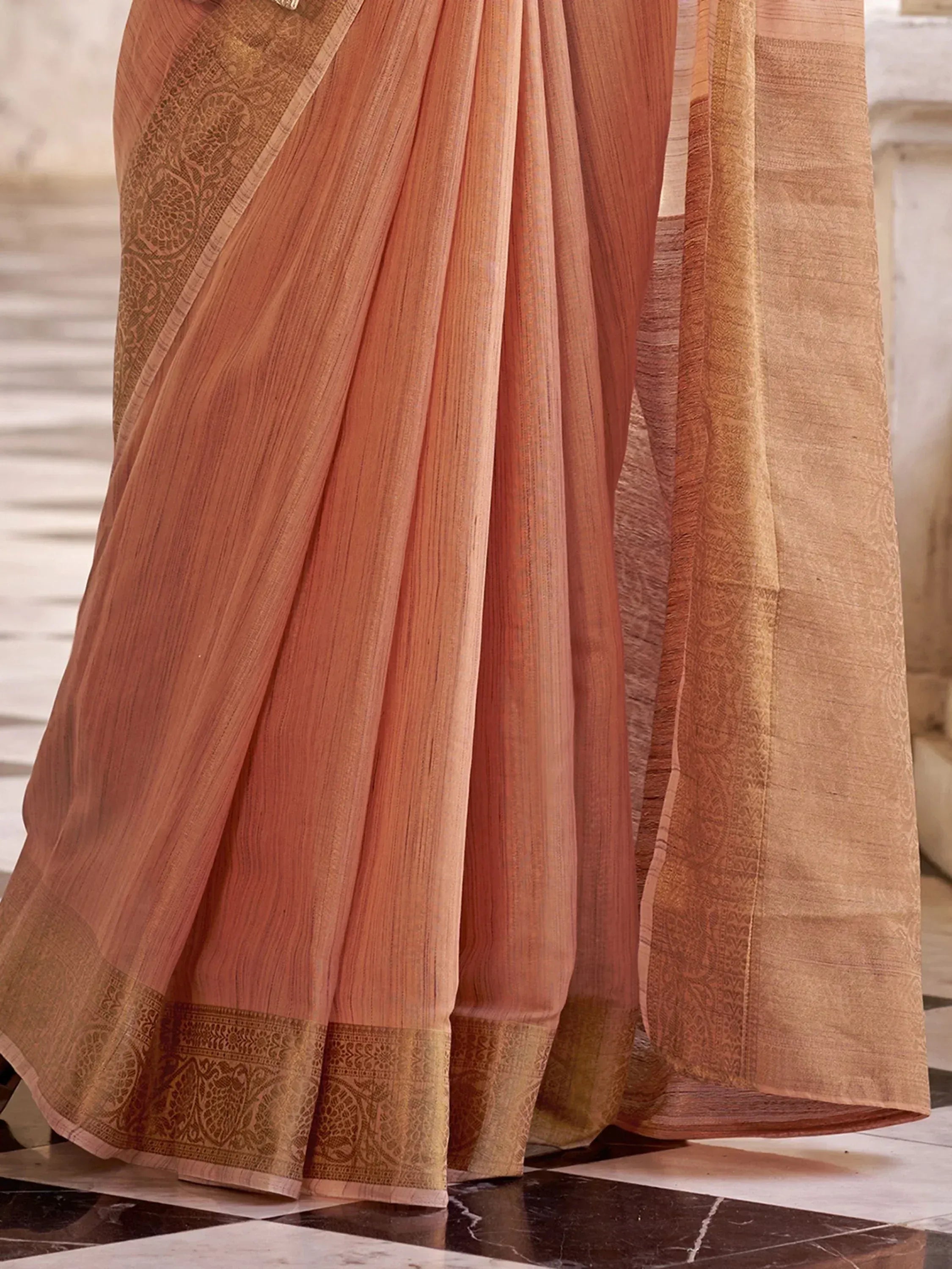 Elegant peach saree with golden zari border and intricate woven patterns, perfect for Indian ethnic occasions.