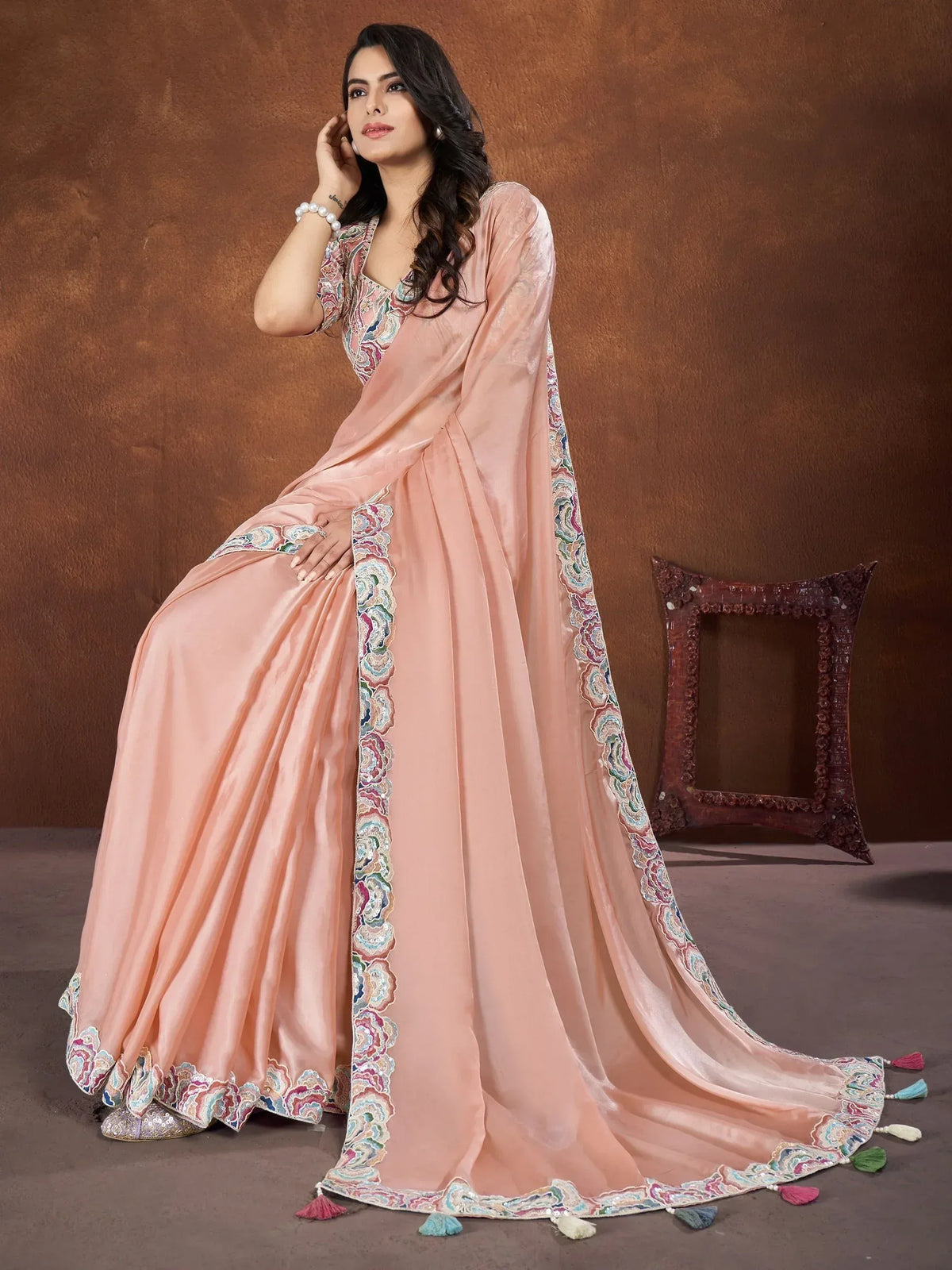 Elegant peach designer saree with colorful floral embroidery and tassels, perfect for Indian ethnic occasions