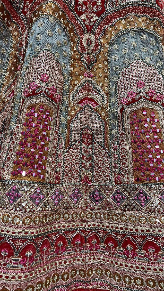 Intricate Indian ethnic wear with mirror work, floral embroidery, and vibrant red-gold patterns