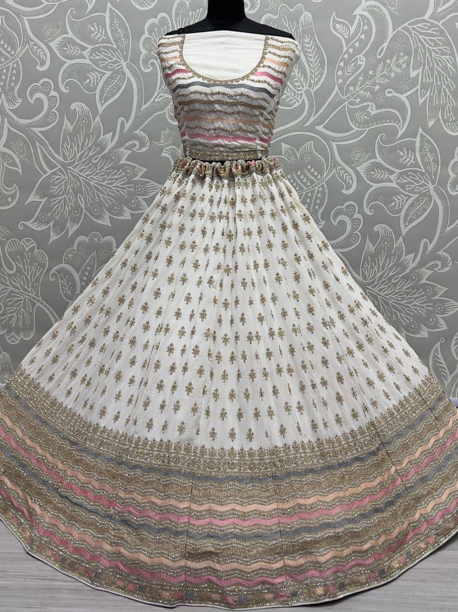 White ethnic gown with gold embroidery and colorful striped border, perfect for Indian festive occasions