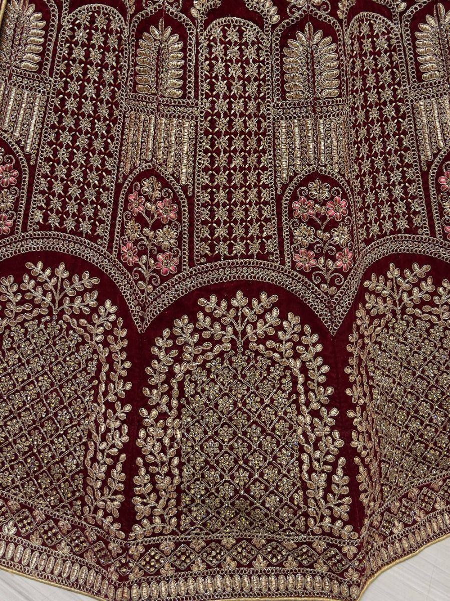 Rich maroon velvet lehenga with intricate gold embroidery and floral motifs, perfect for Indian ethnic wear.