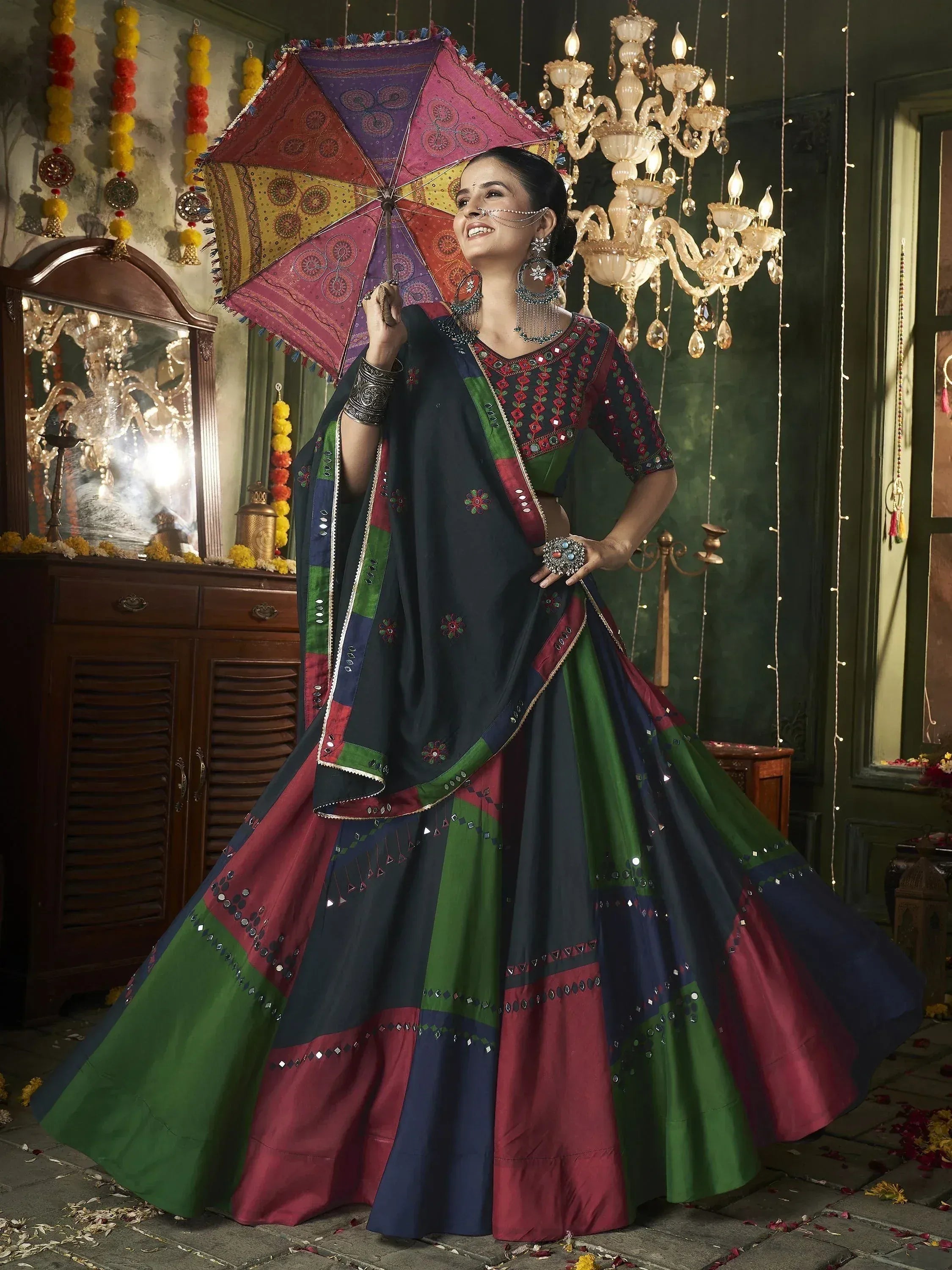 Woman in colorful ethnic lehenga choli with mirror work, holding decorative umbrella, festive Indian attire