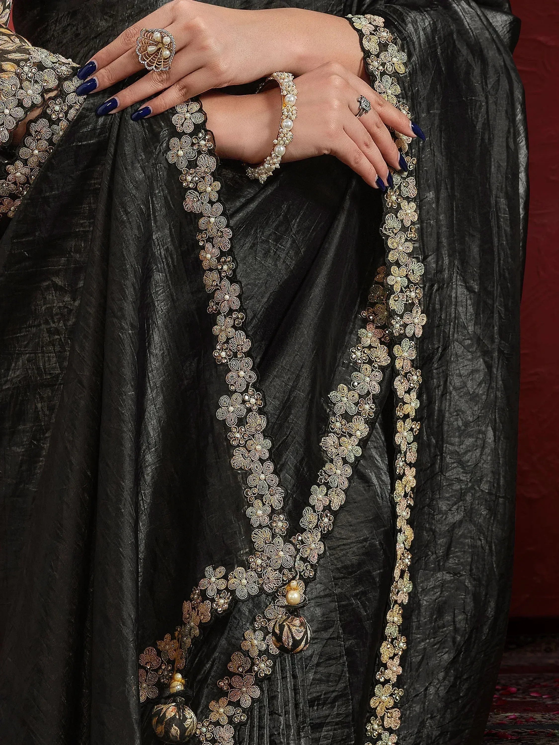 Black ethnic saree with gold floral embroidery and pearl detailing, paired with statement jewelry
