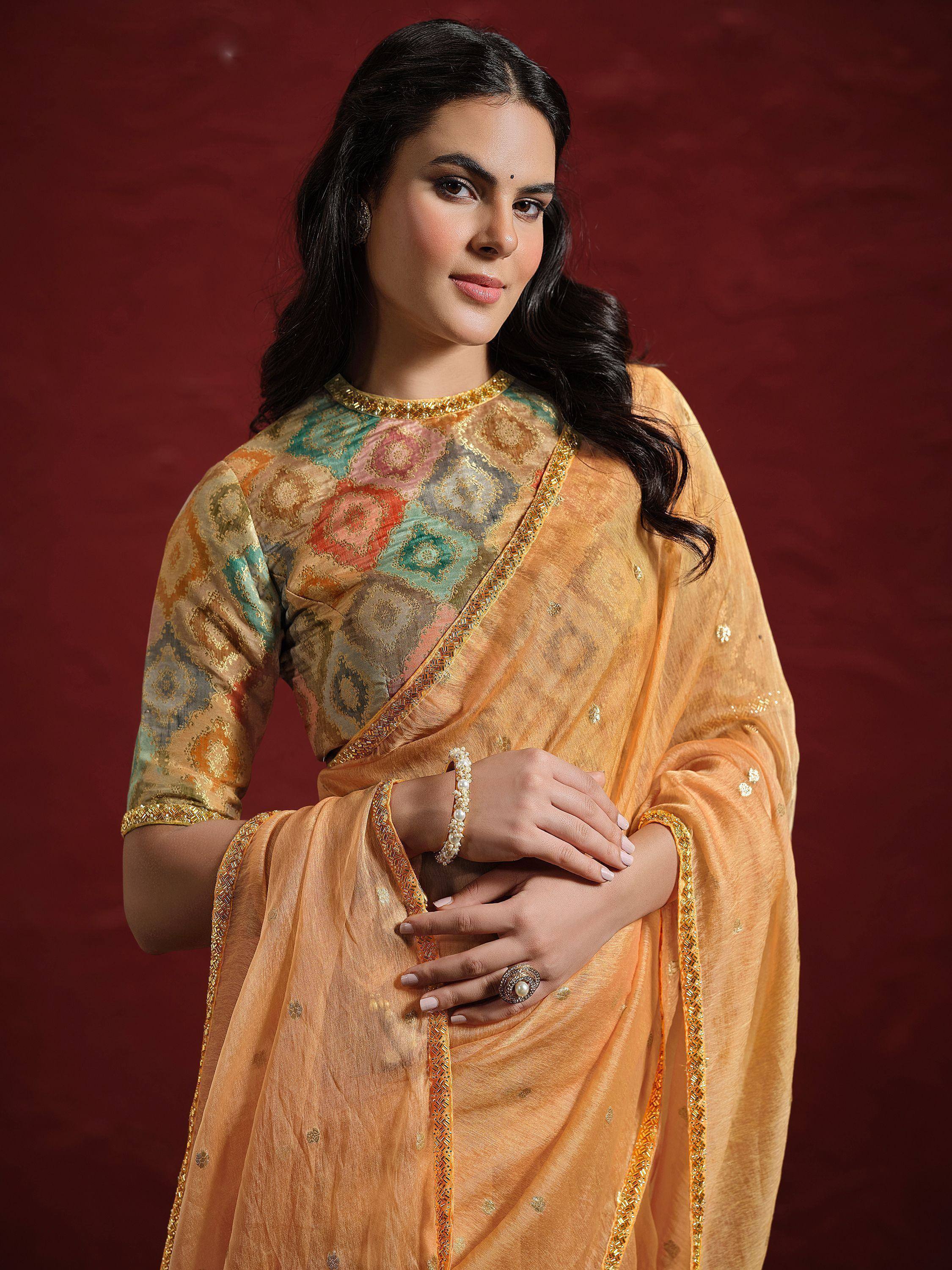 Woman in elegant orange saree with gold embroidery and colorful floral blouse, traditional Indian ethnic wear